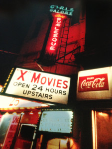 In 1977, the neon lights of an adult establishment glow on the east side of 41st and Eighth Avenue—where the New York Times building now stands. Adult establishments, including adult video stores, have been moving away from Hell”s Kitchen because of more stringent regulation, redevelopment and a lack of business. Photo: Maggie Hopp.