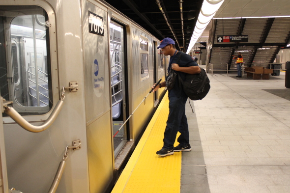 Caption: Hashim Kirkland boards the 7 train at the station, which opened on the 13th. Photo: Jingnan Peng