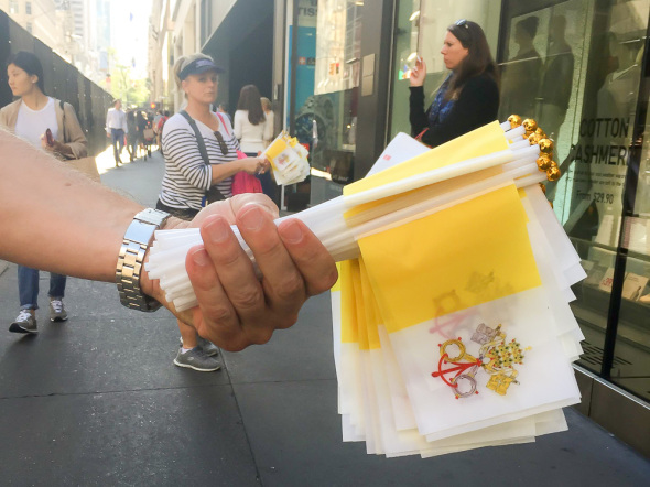 A vendor offers bystanders pope flags for a dollar.