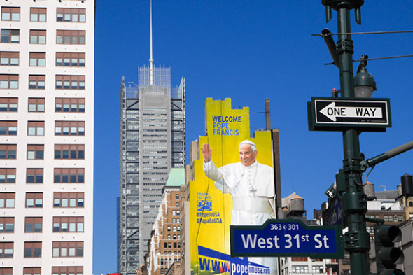 A gigantic banner has been stretched across a building next to West 31st St welcoming the pope, complete with hashtags.