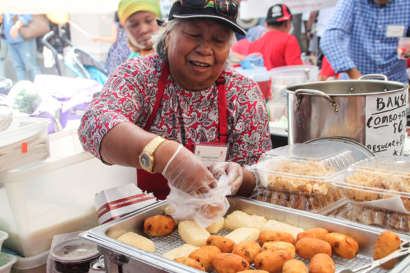 A vendor serves customers combro, a savory cassava based cake native to western Java.