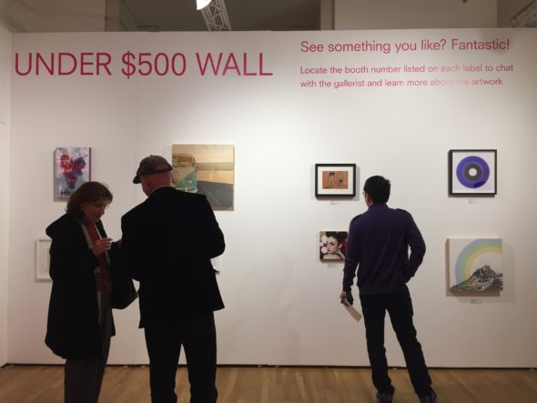 Visitors observing artwork on the fair's "Under $500 Wall." 