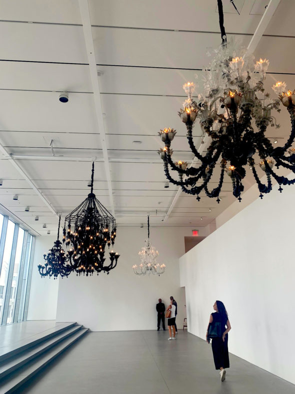 Beautiful and intricate black and white chandeliers inside a gallery. 